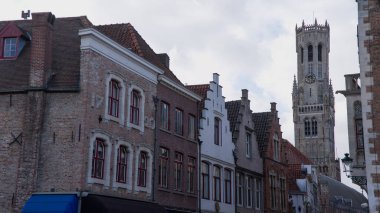 BRUGES, BELGIUM - 15 Eylül 2025 - Bruges 'de ortaçağ çan kulesi bulutlu bir gökyüzüne karşı yükselen binalar