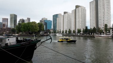 ROTTERDAM, NETHERLANDS - 13 Eylül 2025 - Rotterdam, Hollanda, nehir boyunca kentsel ufuk çizgisi ile hareket eden bir su taksisi