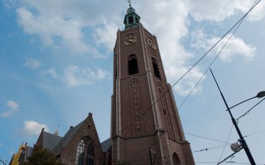 HAGUE, NETHERLANDS - 14 Eylül 2025 - Grote Kerk kilise saat kulesi Lahey 'deki bulutlu mavi gökyüzüne karşı yükseliyor