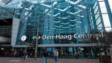 HAGUE, NETHERLANDS - 14 Eylül 2025 - Hollanda, Lahey 'deki Den Haag Centraal tren istasyonunun modern cam cephesinde yürüyen insanlar