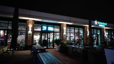 SCHENINGEN, NETHERLANDS - 14 Eylül 2025 - Gıda binasının dış yüzeyi neon ışıklı ve geceleri parlayan açık hava oturma alanları