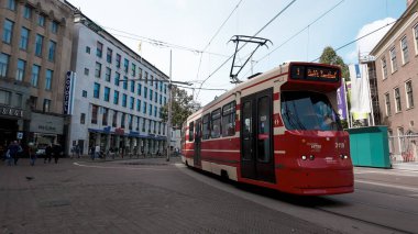 HAGUE, NETHERLANDS - 14 Eylül 2025 - Hollanda, Lahey 'deki işlek bir şehir caddesinde seyahat eden kırmızı ve beyaz tramvay