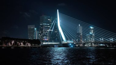 ROTTERDAM, NETHERLANDS - 13 Eylül 2025 - Erasmus Köprüsü Rotterdam şehri ve Maas Nehri 'ni gece aydınlatmaktadır.