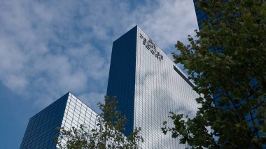 ROTTERDAM, NETHERLANDS - 13 Eylül 2025 - De Delftse Poort gökdeleni mavi gökyüzünü ve bulutları yansıtan cam bir cepheye sahiptir.