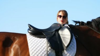 Genç bir kız, bir binici, bir jokey at üstünde, eyer, bacağını atma oturur.