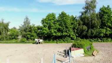 yukarıdan görüntülemek, havadan video çekim, eğitim kum alan, Bahçesi, biniciler, jockeys binmek atlar, atlarla bariyer yanında çeşitli egzersizler gerçekleştirin. yaz, açık havada,