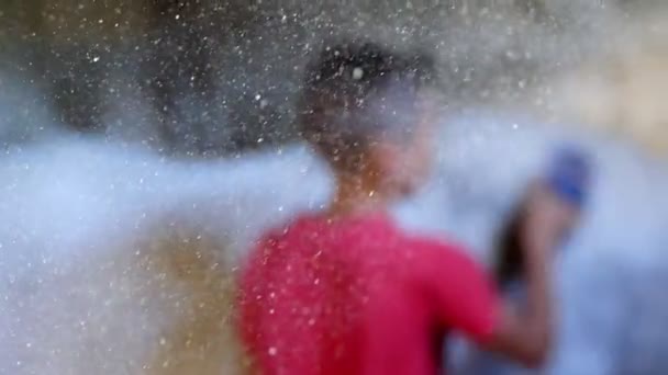 In the stable, a child is a boy, cares for a horse, combs it with a special brush, in the rays of light, dust particles are seen, they glow. close-up of the shining grains of dust — Stock Video