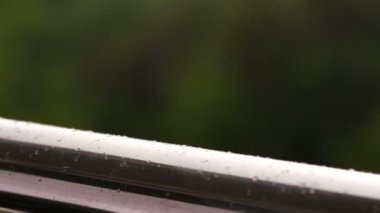 yakın çekim, büyük metal gümüş renk korkuluk üzerine yağmur damlaları. bir arka plan bulanık yeşillik