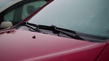 dış, oradan görünümdür şiddetli yağmur duş, damla düşmek araba kaput, ön cam silecekleri boş kırmızı araba ile Park yerinde ayakta. aşağı damlacıklar akışında küçük akarsu