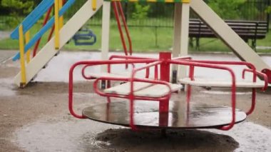 Yuvarlak atlıkarınca yağmurda, ıslak boş merry go rüzgarda yalnız döner. şiddetli bir yağmur sağanak ile güçlü bir rüzgar. oyun, yaz yağmurlu bir gün büyük su birikintileri