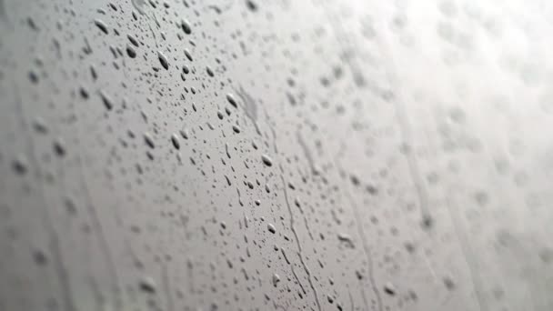 Крупным планом, на стекло машины капли дождя стекают по множеству ручьев. Проливается сильный дождь. капли дождя на стекле автомобиля — стоковое видео
