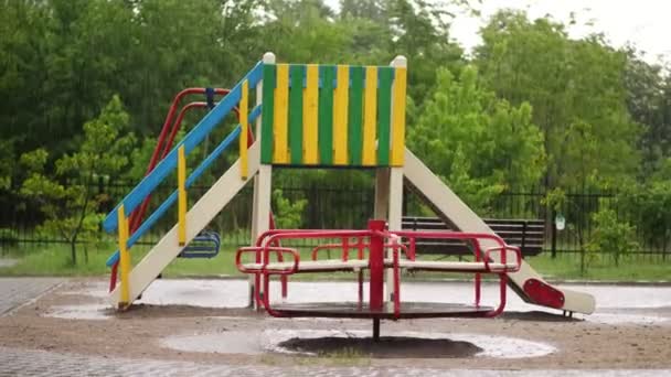 Egy üres játszótér alatt nagy mennyiségű eső, erős szél és felhőszakadás. nagy pocsolya, nyári esős nap — Stock videók