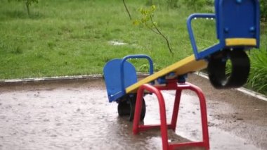 ağır yağmur, güçlü bir rüzgar ile şiddetli bir yağmur altında boş bir oyun alanı. büyük su birikintileri, yaz yağmurlu bir gün