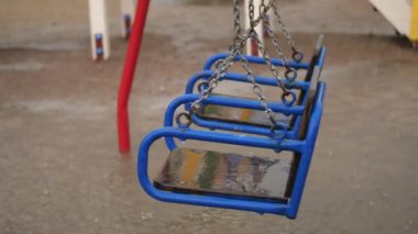 Boş salıncak yağmurda, rüzgarda sallanan drenches. şiddetli bir yağmur, bir fırtına, güçlü bir rüzgar ile şiddetli bir yağmur. Bahçede işte bir çocuk oyun alanı ile büyük su birikintileri, yaz