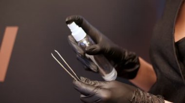 Güzellik Salonu. yakın çekim, Şevval özçelik güzellik siyah lastik eldiven eller cımbız kaşları için tutun ve antiseptik ile sprinkles