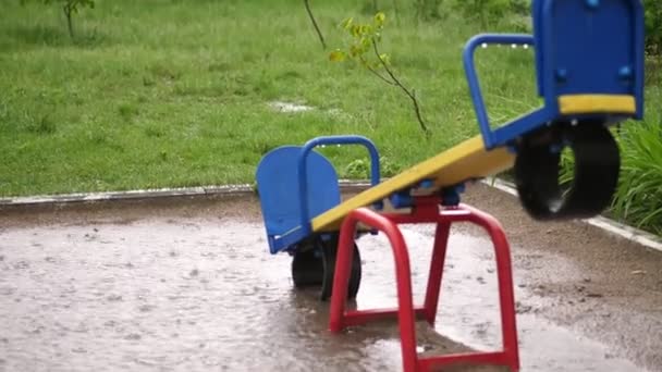 Um parque infantil vazio sob forte chuva, um aguaceiro com um vento forte. grandes poças, verão dia chuvoso — Vídeo de Stock