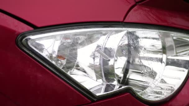 Close-up, koplamp van auto. douche, zware druppels vallen met Water plonsen, op natte oppervlak van rode auto kap, glas koplamp. auto krijgt natte onder zware regen, — Stockvideo