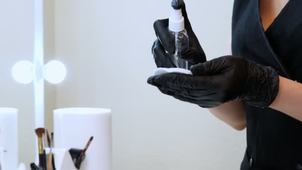 kosmetický salon. detail, mistr v černé speciální rukavice drží vatovým tampónkem a posype se antiseptikum