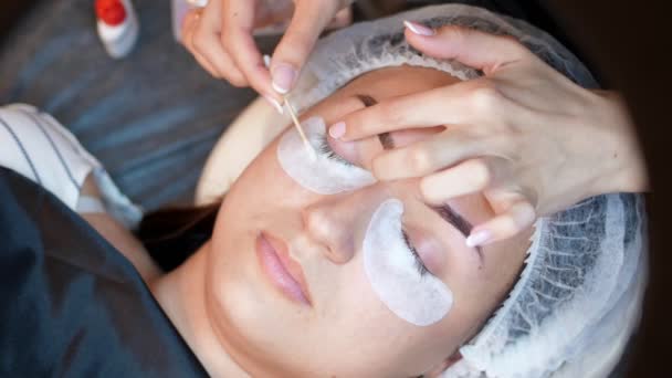 Beauty saloon. close-up, procedure for eyelash extension. the master wipes the eyelashes to the client with a cotton swab soaked in antiseptic, prepares the client for the procedure — Stock Video