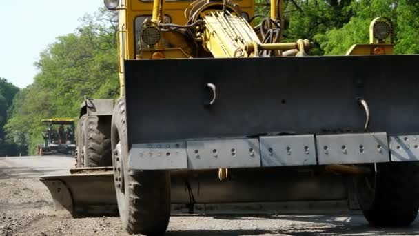 Obras de construção de estradas, reparação de uma estrada, O trator está nivelando cascalho na estrada, fazendo uma base para a colocação do asfalto — Vídeo de Stock