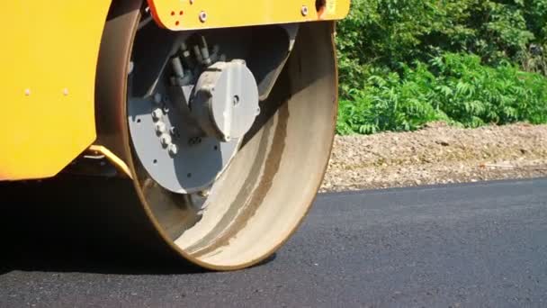 Yakın çekim, yol yapımı silindir kompaktör makine, asfalt finisher ile çalışır. Taze asfalt kaplama üzerine çakıl yol yapımı sırasında temel döşeme yol silindiri — Stok video