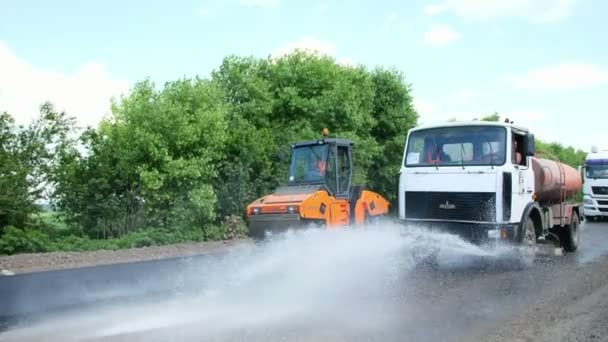 Cherkassy Region, Ukrayna - 31 Mayıs 2018: bir otoyol tamiri, yol yapımı çalışır. Trafik bir tarafında kapsayan özel sulama makine sprinkles su yeni taze asfalt kaplama,. — Stok video