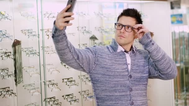 sexy pohledný mladý muž v brýlích, brýle dělá selfie na partnerském obchodě, optika, optik maloobchodě, brýle shop, muž zíral na kameru v jeho mobilní telefon