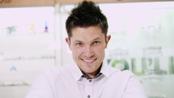 Portrait of sexy smiling Handsome man staring at camera. holding lots of colorful spectacles, sunglasses, at the same time in his hands, in front of his face. man dressed in white shirt — Stock Video