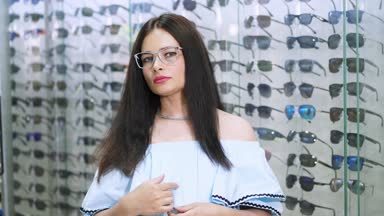 seksi güzel kadın kameraya bakıyor. Portre gülümseyen kadın müşterinin optik deposunda bir gözlükçü perakende mağaza gözlük takıyor. gözlük ve arka plan üzerinde bir sürü