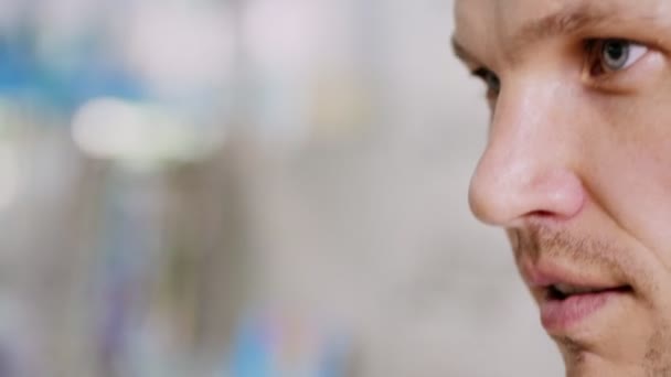 Primer plano, retrato del hombre guapo probándose gafas de sol en la tienda óptica. en espectáculos se refleja el escaparate de la óptica y al lado de pie hermosa mujer — Vídeos de Stock