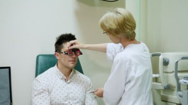 Kadın Optometrist yapıyor görüş test için hasta, hastane phoropter, optometrist deneme çerçeve, görsel kontrol cihaz ile. Vizyon doktor ofisinde denetler