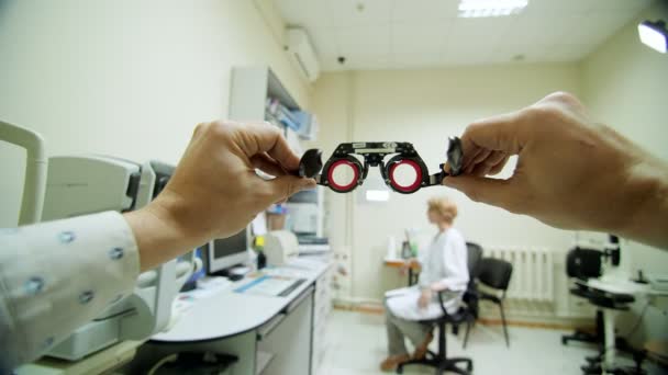 Οπτικής γυαλιά πλαισίων γκρο πλαν, Οφθαλμίατρος εξετάζει ασθενή με οπτομέτρη δοκιμή πλαίσιο, οπτική επιθεώρηση συσκευή στην Οφθαλμολογική κλινική, — Αρχείο Βίντεο