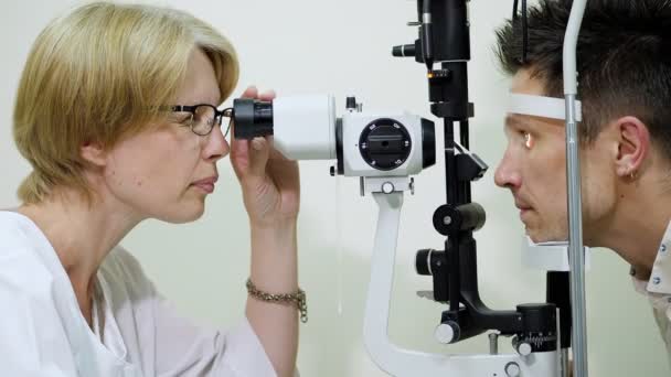 Optometrista médico femenino, oftalmólogo con tonómetro sin contacto es cheking pacientes visión, presión intraocular en clínica ocular o tienda de óptica, laboratorio oftalmilógico . — Vídeo de stock