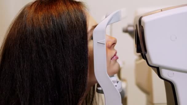 Primer plano de la cara, mujer que hace la prueba del ojo con el tonómetro sin contacto, visión que hace ruido, presión intraocular en la clínica óptica, laboratorio oftalmilógico — Vídeo de stock