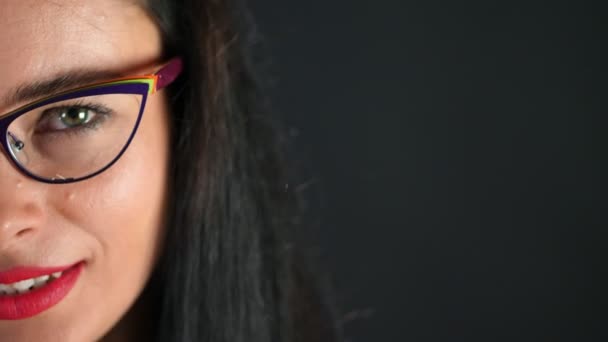 Retrato de una mujer morena sexy con labios rojos que erótica y juguetonamente se prueba gafas con estilo, gafas y mirando sexualmente a la cámara en el estudio. fondo gris oscuro . — Vídeo de stock