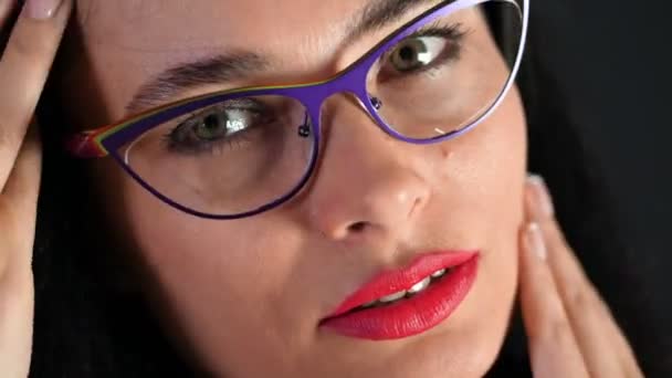 一个性感的黑发女人的肖像, 红唇谁 eroticly 和开玩笑尝试时尚眼镜, 眼镜, 并在相机在演播室的性。深灰色背景. — 图库视频影像