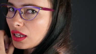 kırmızı seksi esmer kadın portresi kim eroticly dudakları ve şakacı şık gözlük, gözlük ve kamera Studio cinsel açıdan bakarak çalışır. koyu gri arka plan.