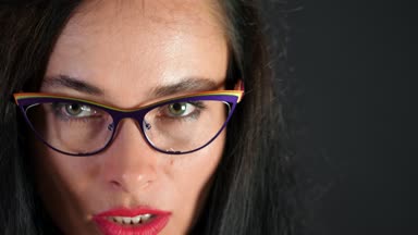 kırmızı seksi esmer kadın portresi kim eroticly dudakları ve şakacı şık gözlük, gözlük ve kamera Studio cinsel açıdan bakarak çalışır. koyu gri arka plan.