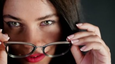 kırmızı seksi esmer kadın portresi kim eroticly dudakları ve şakacı şık gözlük, gözlük ve kamera Studio cinsel açıdan bakarak çalışır. koyu gri arka plan.