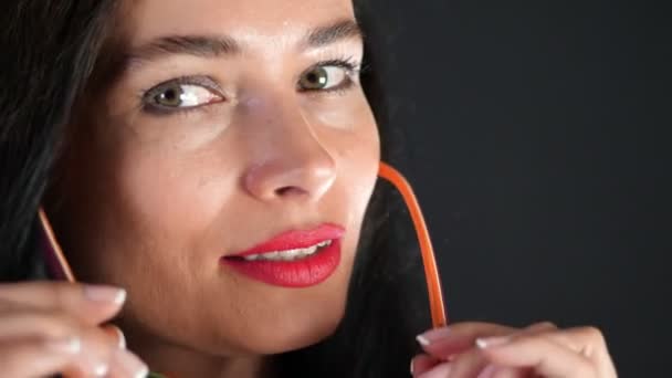 Retrato de una mujer morena sexy con labios rojos que erótica y juguetonamente se prueba gafas con estilo, gafas y mirando sexualmente a la cámara en el estudio. fondo gris oscuro . — Vídeos de Stock