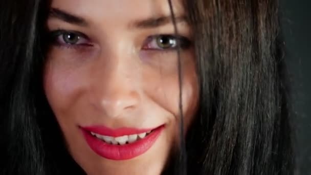 Retrato de una mujer morena sexy con labios rojos que erótica y juguetonamente se prueba gafas con estilo, gafas y mirando sexualmente a la cámara en el estudio. fondo gris oscuro . — Vídeo de stock