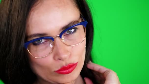 Fundo verde, cromeakey. retrato de uma mulher morena sexy com lábios vermelhos, em óculos elegantes, óculos, eroticly, brincando se move, olhando sexualmente para a câmera, posando em estúdio . — Vídeo de Stock