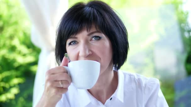 Retrato de agradable sonrisa, feliz hermosa real 40 años de edad mujer ucraniana. una mujer bebe té sin sacar una cucharadita — Vídeos de Stock