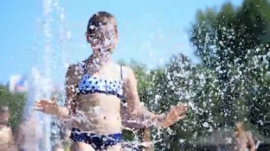 gülümseyen, mutlu sekiz yaşındaki kız sokak şehir Çeşme, açık havada, su sıçramalarına, eğleniyor park, yaz, tatil sırasında sıcak güneşli gün mayo.