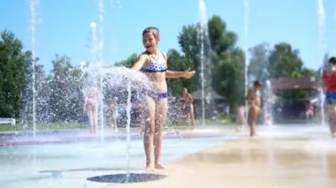 gülümseyen, mutlu sekiz yaşındaki kız sokak şehir Çeşme, açık havada, su sıçramalarına, eğleniyor park, yaz, tatil sırasında sıcak güneşli gün mayo.