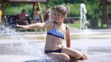 gülümseyen, mutlu sekiz yaşındaki kız sokak şehir Çeşme, açık havada, su sıçramalarına, eğleniyor park, yaz, tatil sırasında sıcak güneşli gün mayo.
