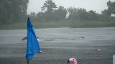 yaz yağmur, fırtına, boş bir plaj, yalnız plaj şemsiye bekliyoruz, ağır yağış güçlü, fırtınalı rüzgar, nehrin üzerinde yavaş yavaş yüzüyor deniz bisikleti, bir duş içine düştü.