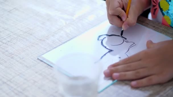 Zeichenunterricht, Großaufnahme, Kinderhände. Mädchen zeichnet Umrisse mit schwarzer Farbe, zeichnet einen Hasen, beherrscht die Technik des Zeichnens auf Glas. — Stockvideo