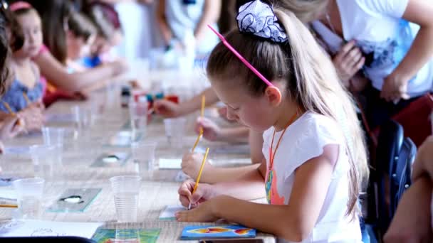 Tekening les in de klas, tekenen kinderen met kleuren, meester de techniek van het tekenen op glas. op de voorgrond trekt een mooi blond meisje van acht-jarige met een passie — Stockvideo