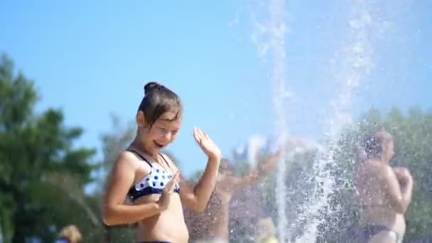 Lachend, blij acht jaar oud meisje in zwembroek plezier in spatten in straat stad fontein, buitenshuis, park, zomer, warme zonnige dag tijdens vakantie. — Stockvideo